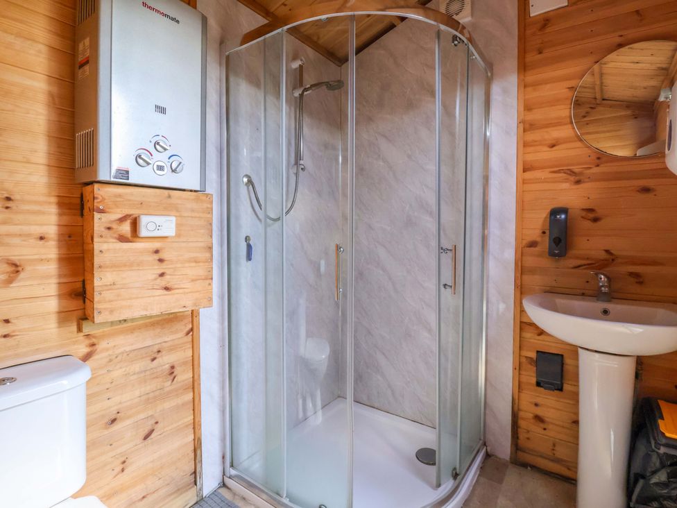 A bathroom with a shower, toilet, and sink at Shepherds hut