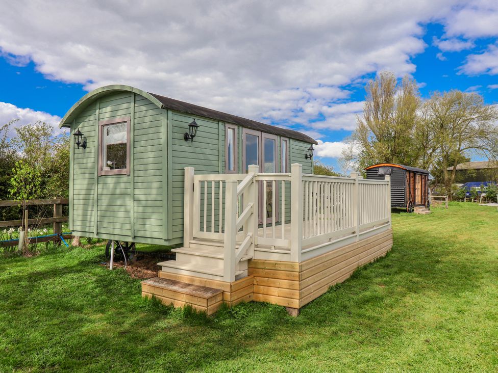 A shepherd's hut with decking and steps in a field at The Dragonfly in Bewholme near Hornsea