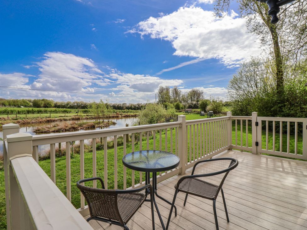 A deck with chairs and a table overlooking a pond at The Dragonfly in Bewholme near Hornsea