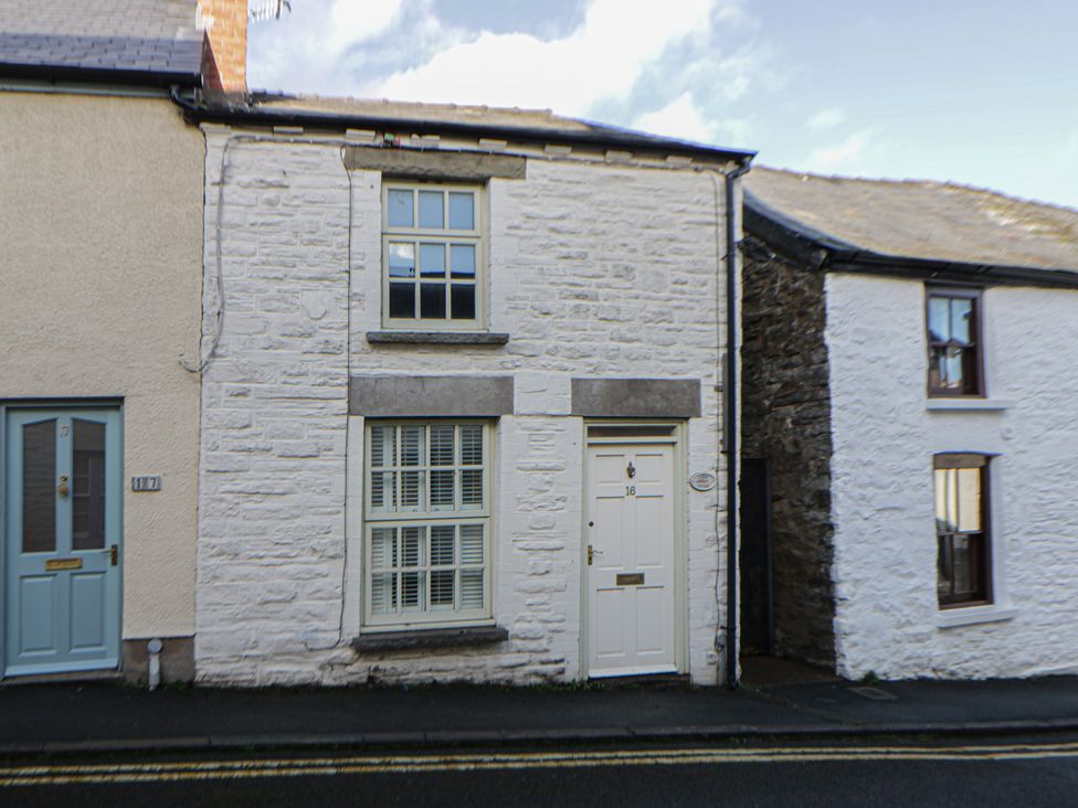 An exterior view of a house with a white facade and a blue door at Cariad Cottage in Hereford