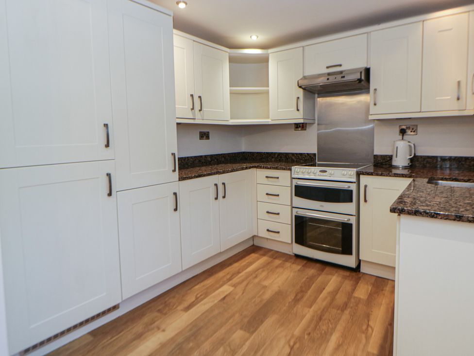 A kitchen with cabinets, stove, and countertop at Cariad Cottage in Hereford