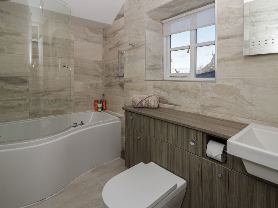 A bathroom with a bathtub, toilet, and sink at Cariad Cottage in Hereford