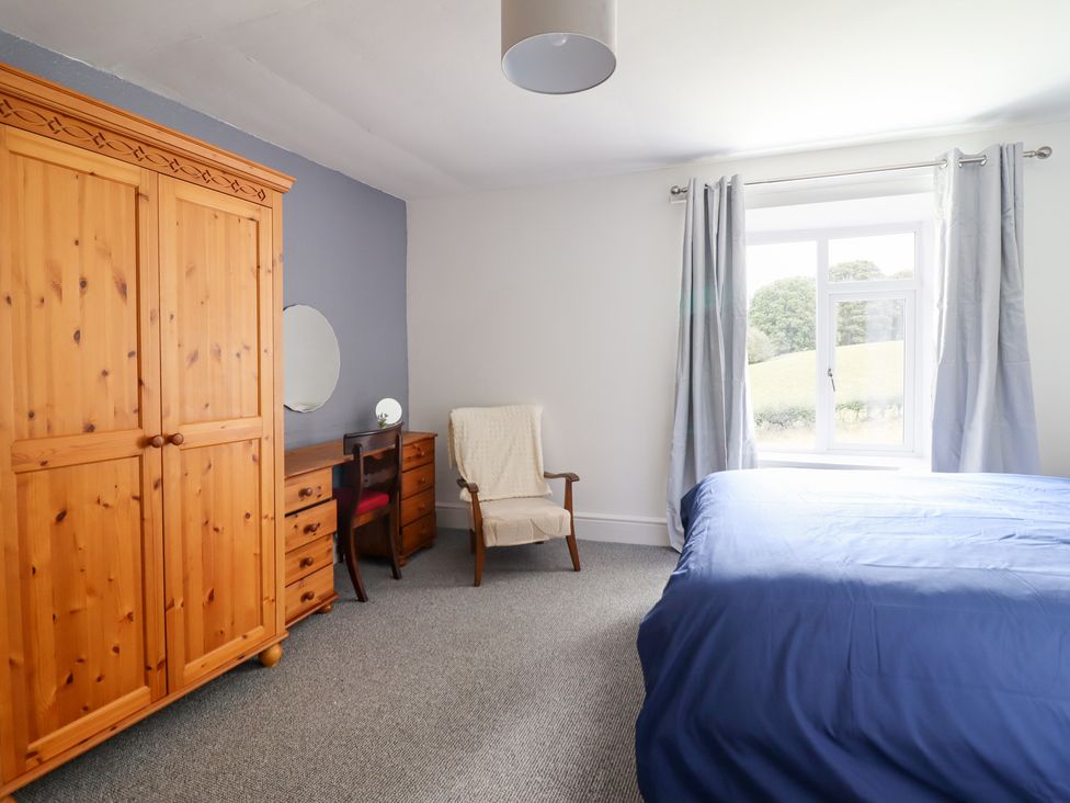 A bedroom with a wardrobe, desk, and bed at Plas Yn Bonwm in Corwen