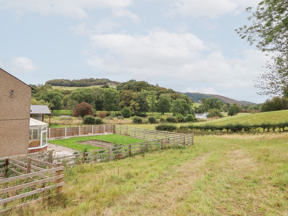 An outdoor area with a fence and conservatory at Plas Yn Bonwm in Corwen