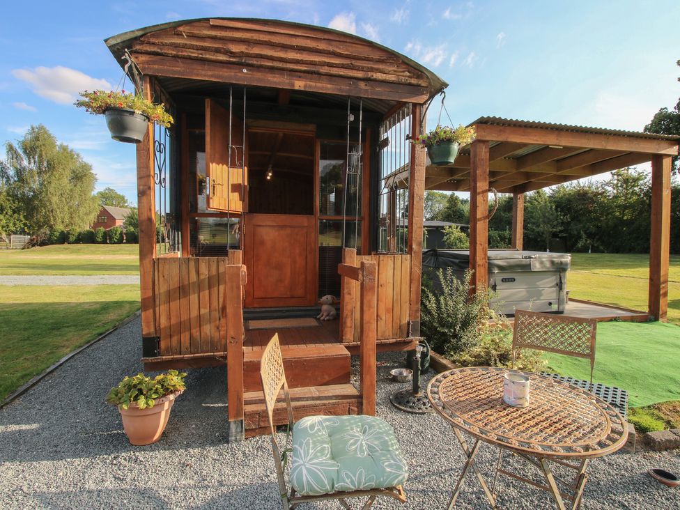 An outdoor area with a shepherd hut and seating at Sharon's Shepherd Hut Oswestry