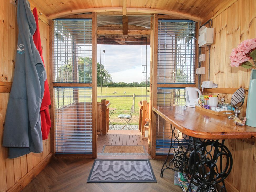 An interior view with a table and chair at Sharon's Shepherd Hut Oswestry