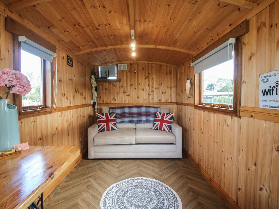A snug with a couch and wooden table at Sharon's Shepherd Hut in Oswestry