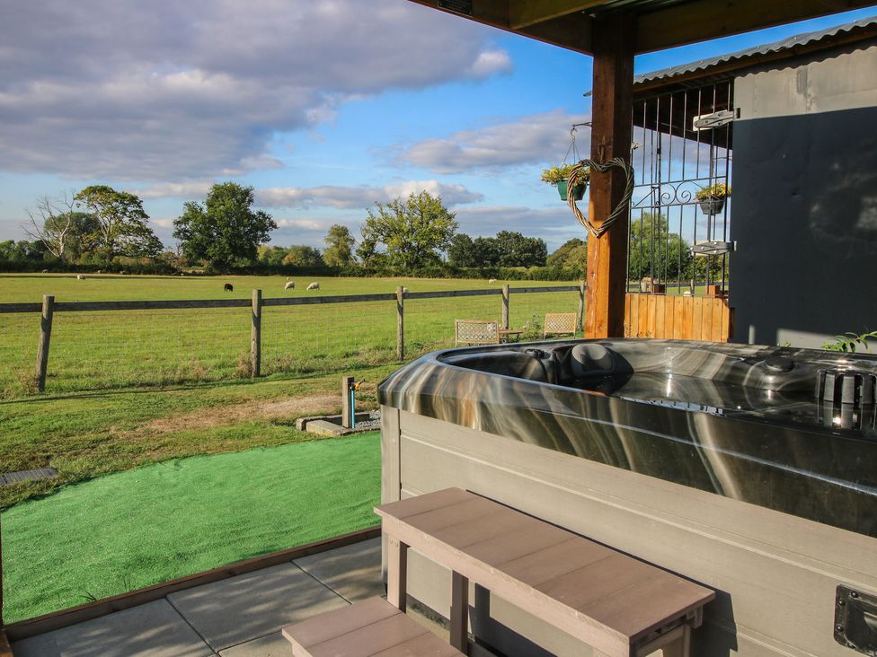 A garden with a hot tub and outdoor seating at Sharon's Shepherd Hut in Oswestry