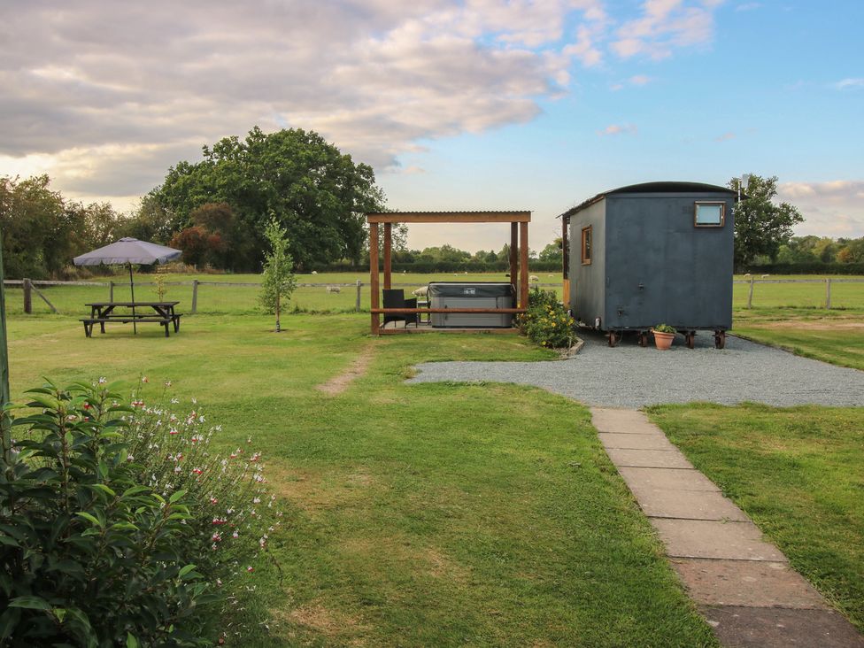 An outdoor area with a shepherd hut and hot tub at Sharon's Shepherd Hut Oswestry