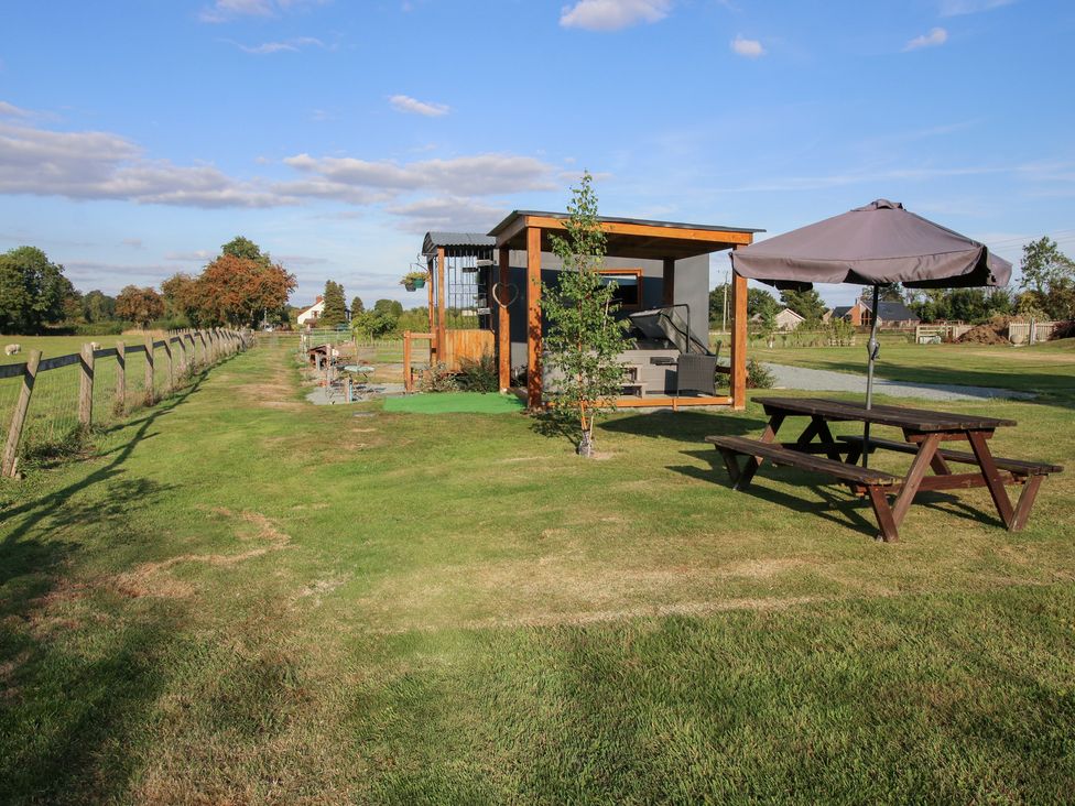 An outdoor area with a hut and picnic table at Sharon's Shepherd Hut Oswestry