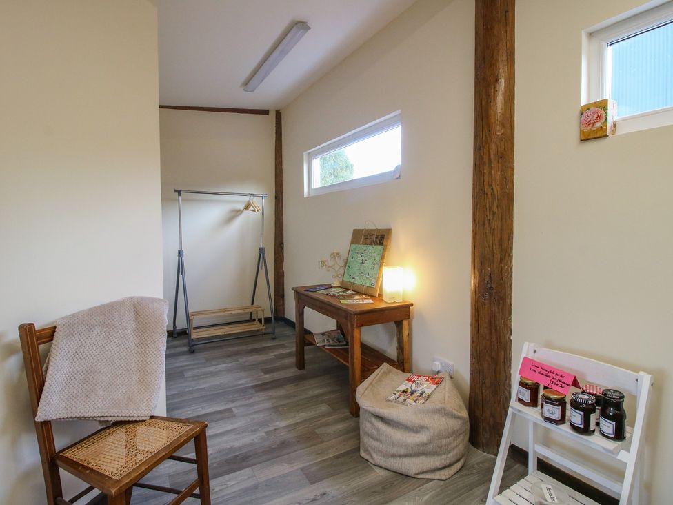 A room with a chair, table, and clothes rack at Sharon's Shepherd Hut in Oswestry