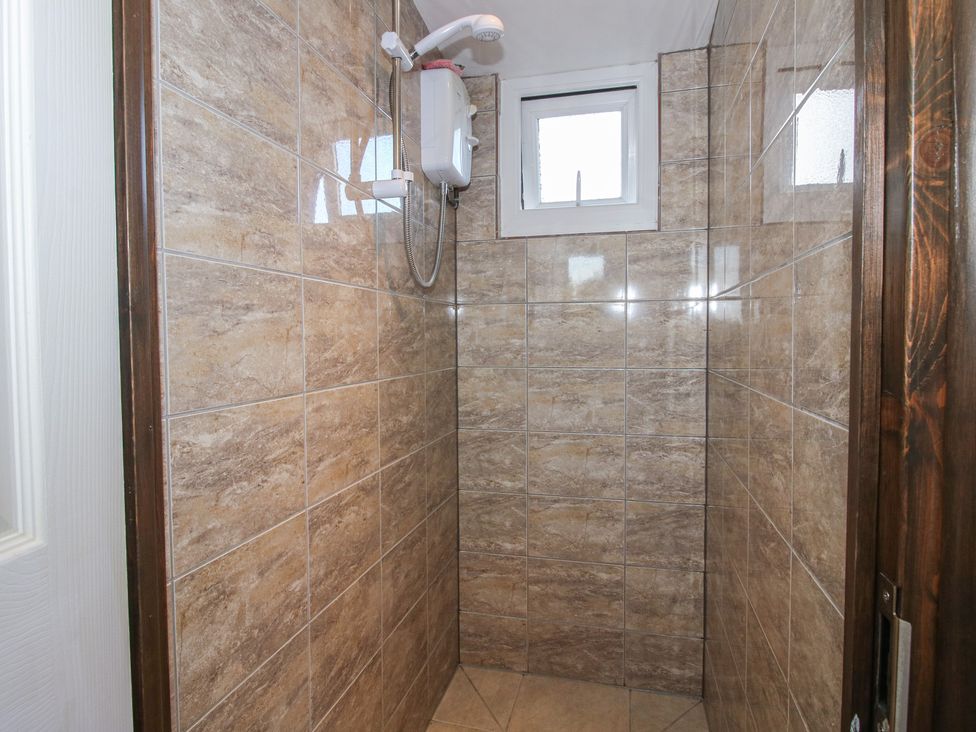 A shower area with tiled walls and a window at Sharon's Shepherd Hut in Oswestry
