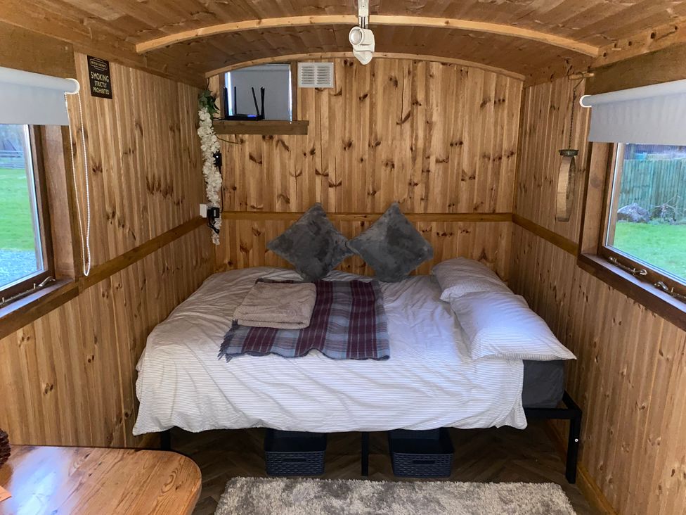 A bedroom with a bed and table at Sharon's Shepherd Hut in Knockin