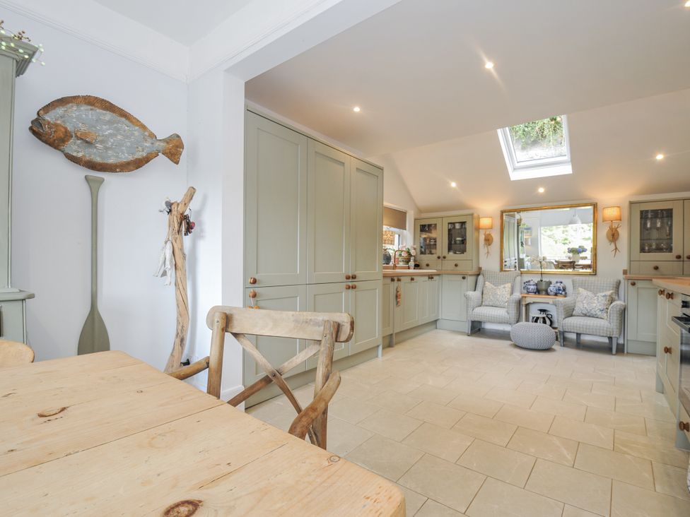 A kitchen with a dining table and cushioned seating at Mayhurst in Looe