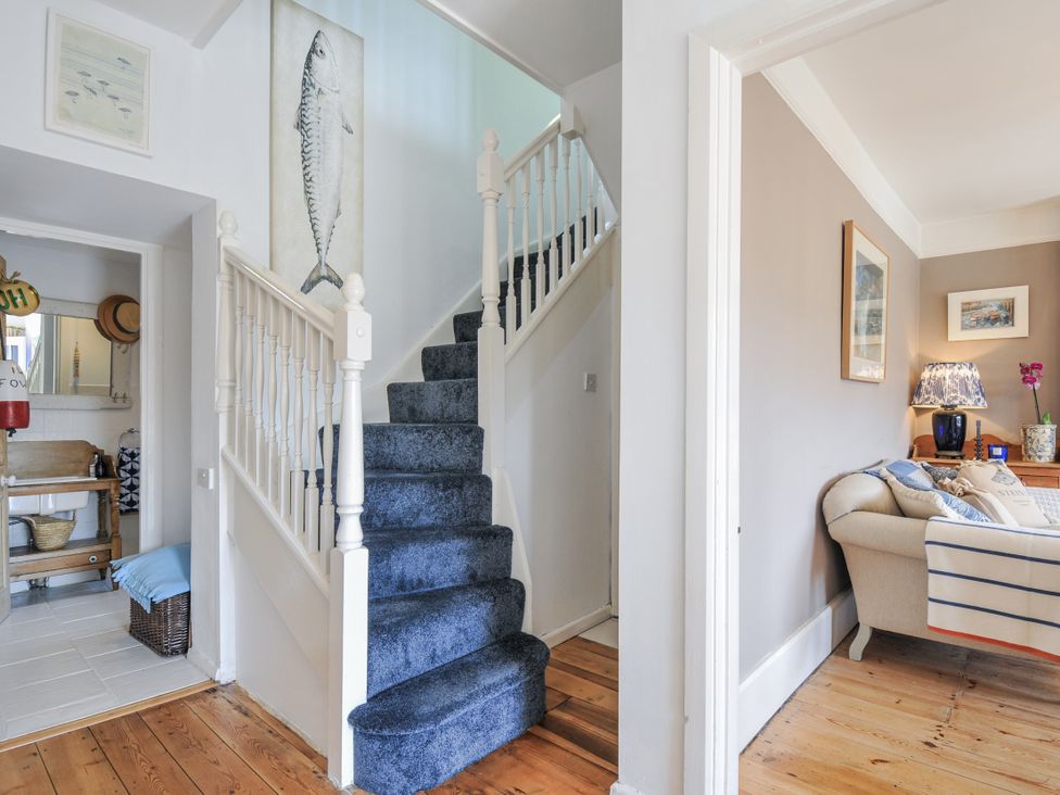 A hallway with a staircase and wall art at Mayhurst in Looe