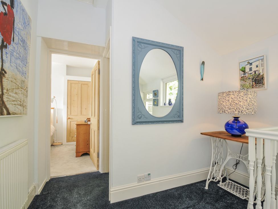 A hallway with a mirror and lamp at Mayhurst Looe