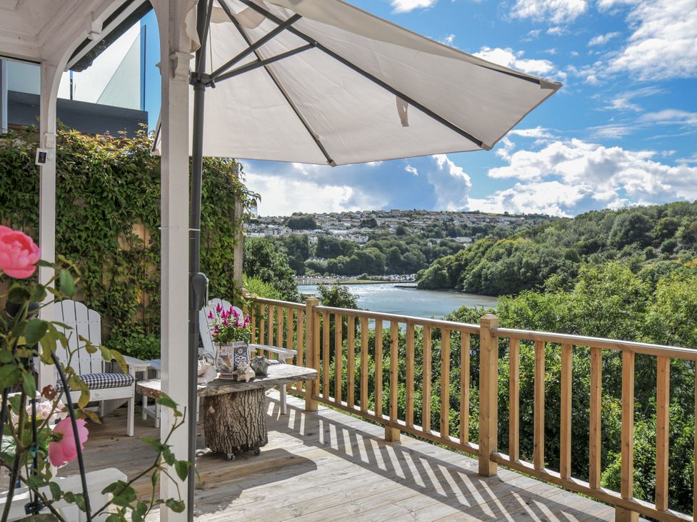 An outdoor space with a table and chairs overlooking a river at Mayhurst in Looe