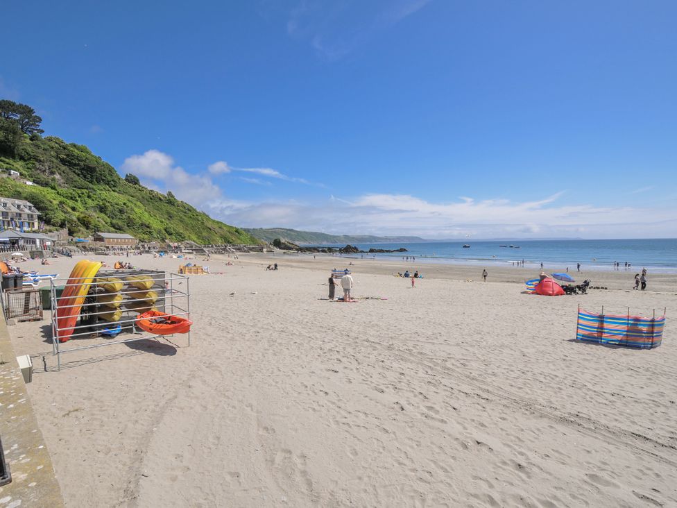 A beach with people and kayaks at Mayhurst in Looe