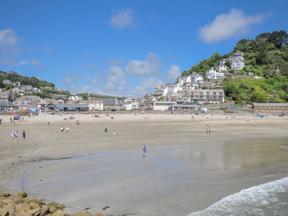 A beach with people walking at Mayhurst in Looe