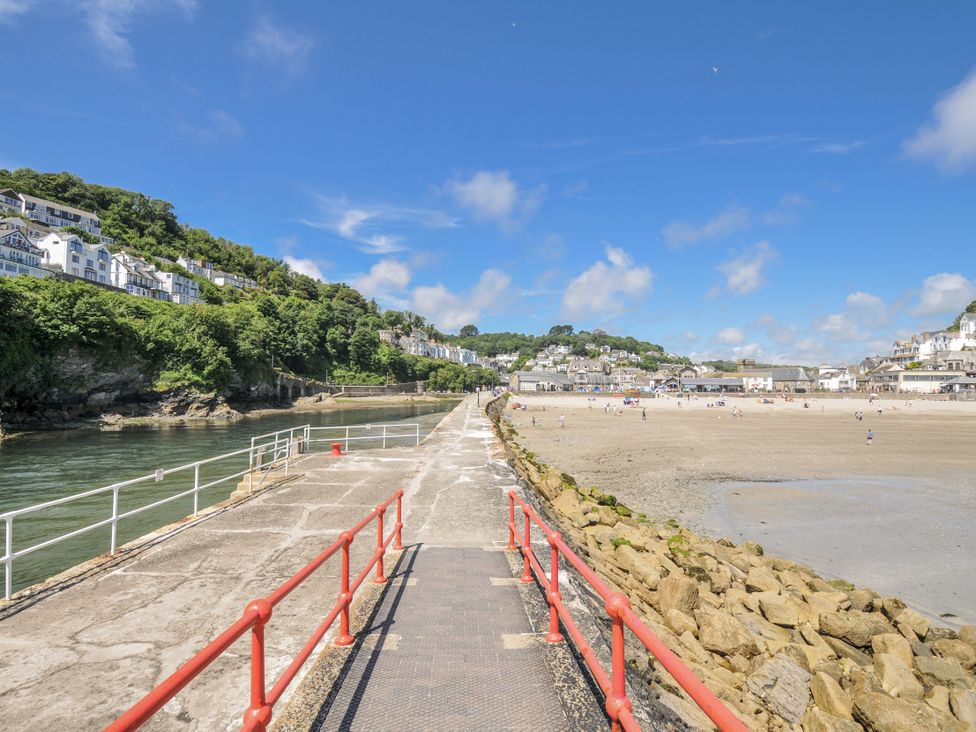 A pier leading to a beach with houses in the background at Mayhurst in Looe