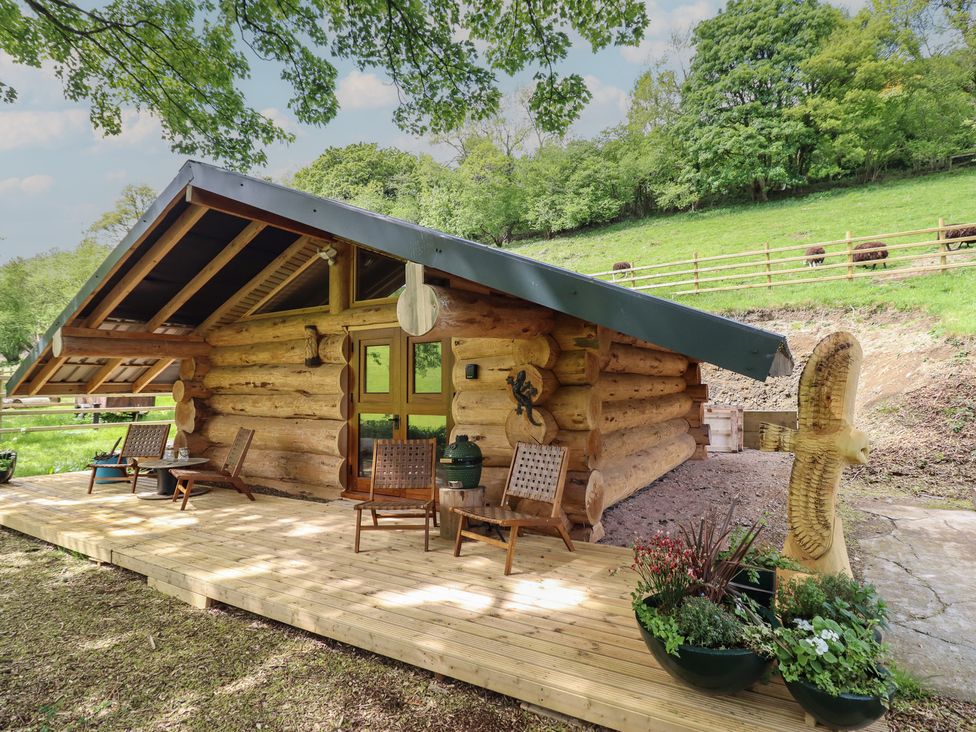 A log cabin with chairs and flower pots at Owl Valley Cabin in Bwlch-y-Ddar near Llanfyllin