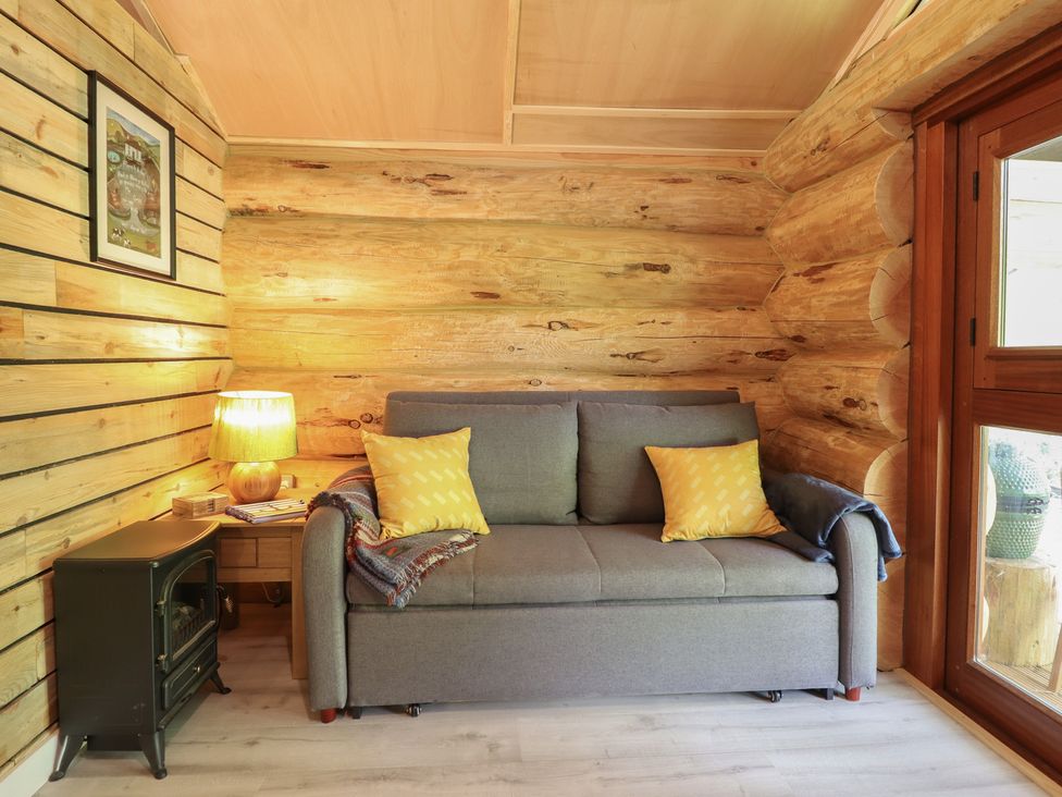 A living room with a sofa and lamp at Owl Valley Cabin in Bwlch-y-Ddar near Llanfyllin