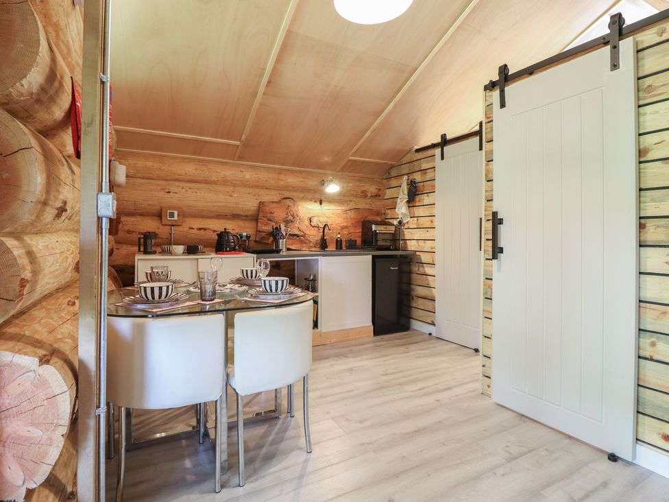 A kitchen with wooden walls and dining table at Owl Valley Cabin near Bwlch-y-Ddar