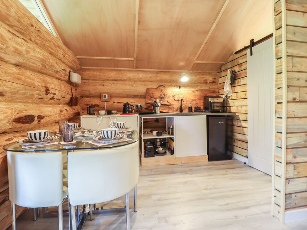 A dining area with a table and chairs in the kitchen at Owl Valley Cabin near Bwlch-y-Ddar near Llanfyllin