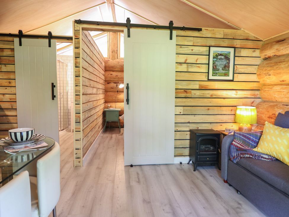 A living room with sliding doors and wooden walls at Owl Valley Cabin in Bwlch-y-Ddar near Llanfyllin
