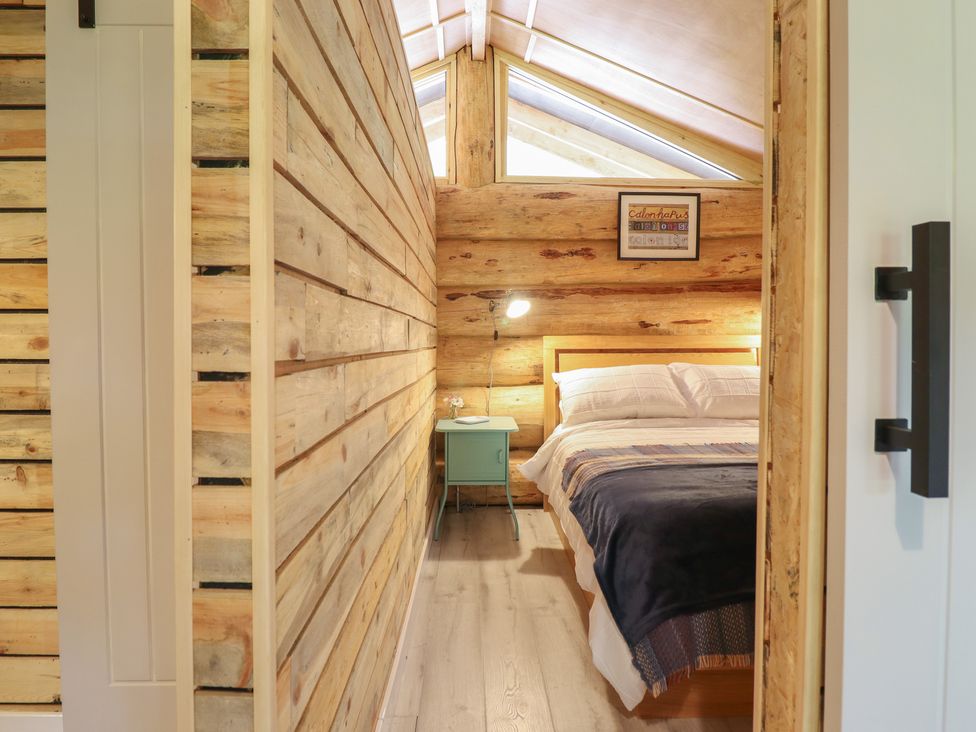 A bedroom with a bed and lamp at Owl Valley Cabin near Bwlch-y-Ddar near Llanfyllin
