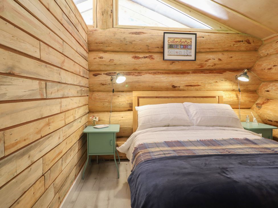 A bedroom with a bed and nightstand at Owl Valley Cabin near Bwlch-y-Ddar