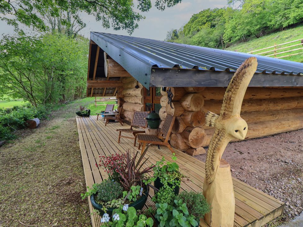 A wooden cabin with a deck and chairs at Owl Valley Cabin in Bwlch-y-Ddar near Llanfyllin