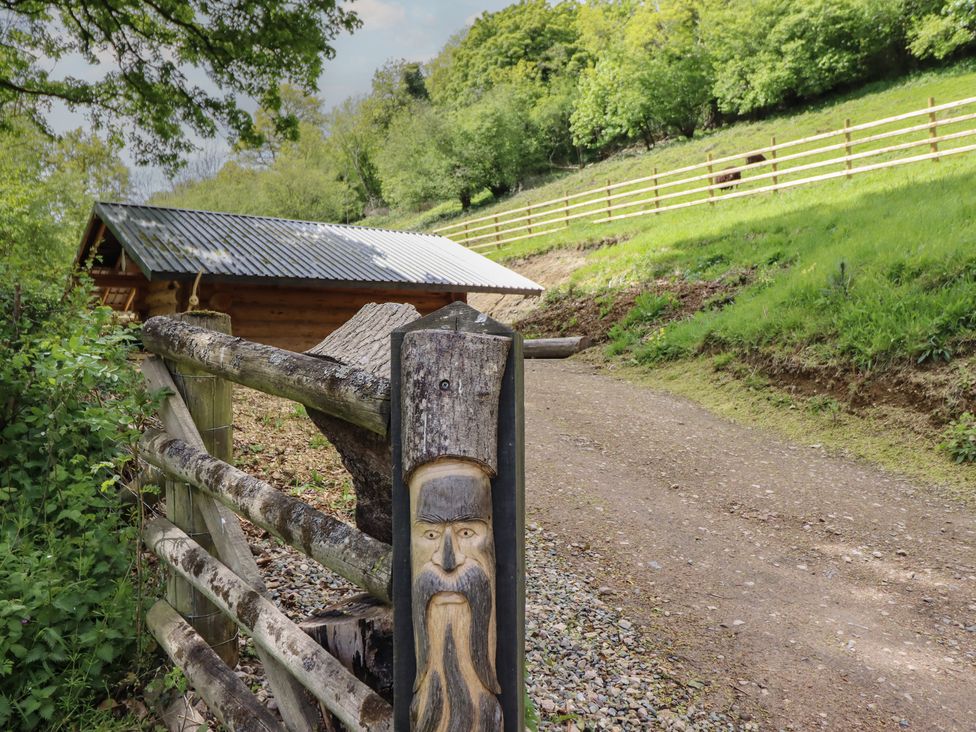 A wooden cabin and a carved figure near a dirt path at Owl Valley Cabin Bwlch-y-Ddar near Llanfyllin