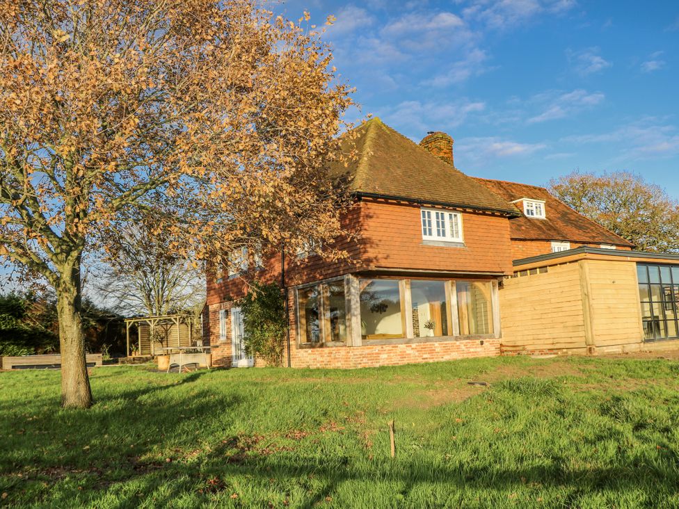 A house with large windows and a tree in a garden at Farm house