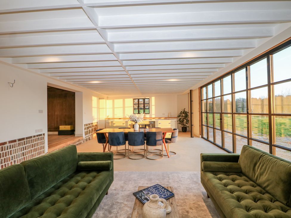 A living room with a dining area and glass walls at Farm house