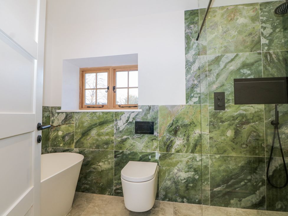 A bathroom with a bathtub, toilet, and window at the Farm house