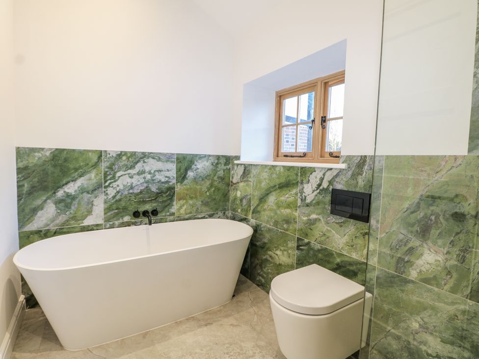 A bathroom featuring a bathtub and toilet with green tiles at Farm house