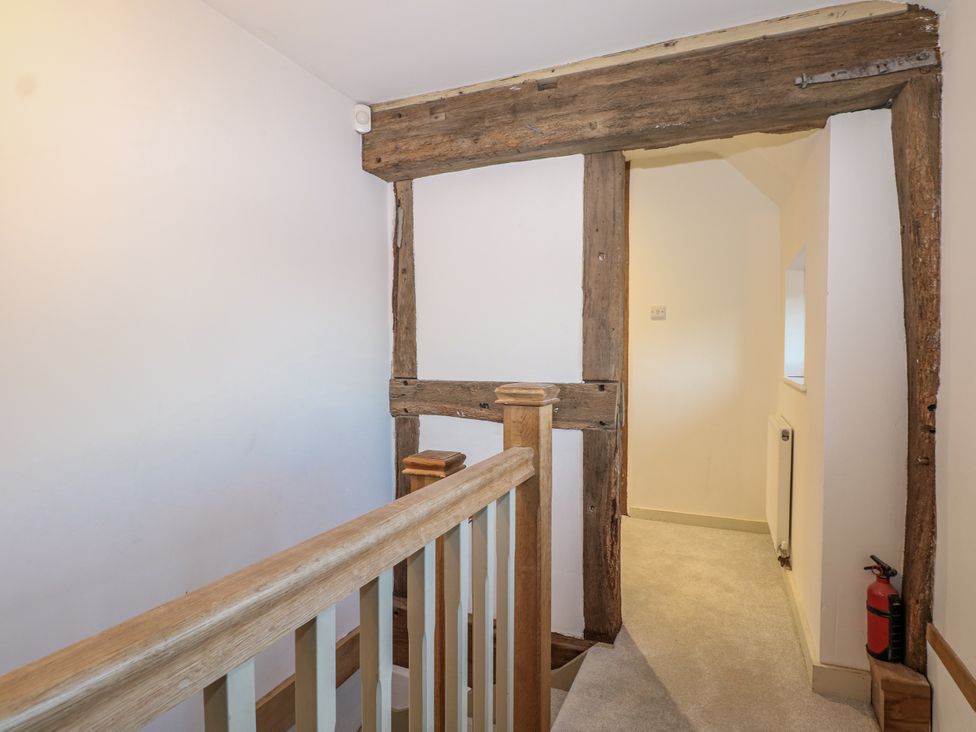 A staircase with a wooden railing in a hallway at Farm house