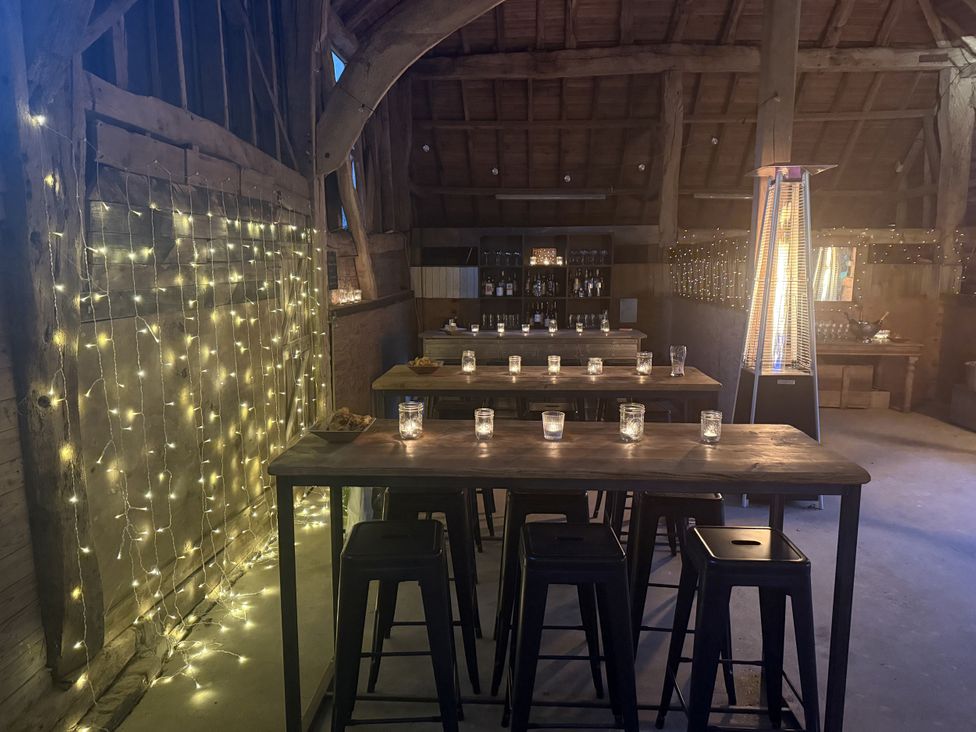 A barn with tables and stools set up with candles at Farm house in North Chailey