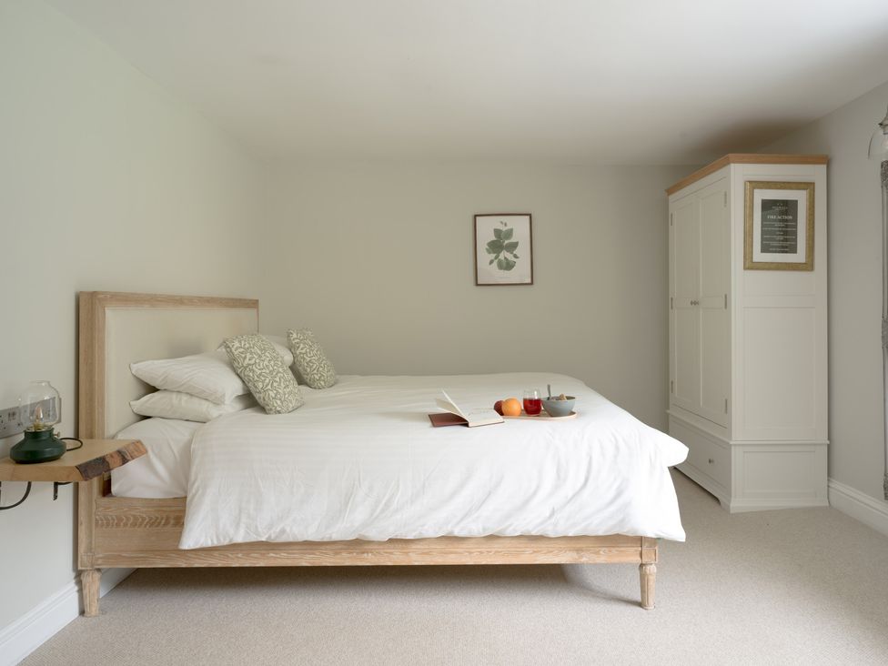 A bedroom with a bed, nightstand, and wardrobe at Holwell Farmhouse in Bampton