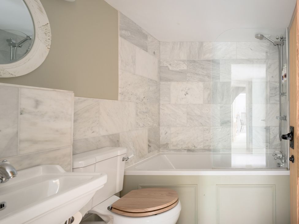 A bathroom with a sink, toilet, bathtub and shower at Holwell Farmhouse in Bampton