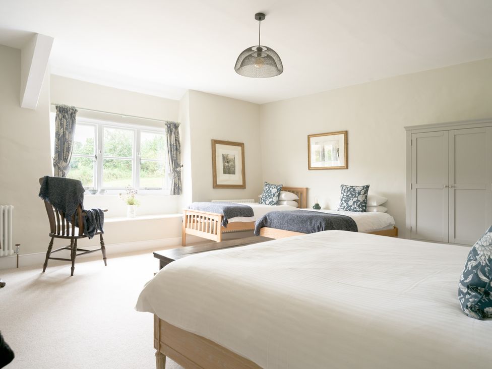 A bedroom with two beds and a window at Holwell Farmhouse in Bampton