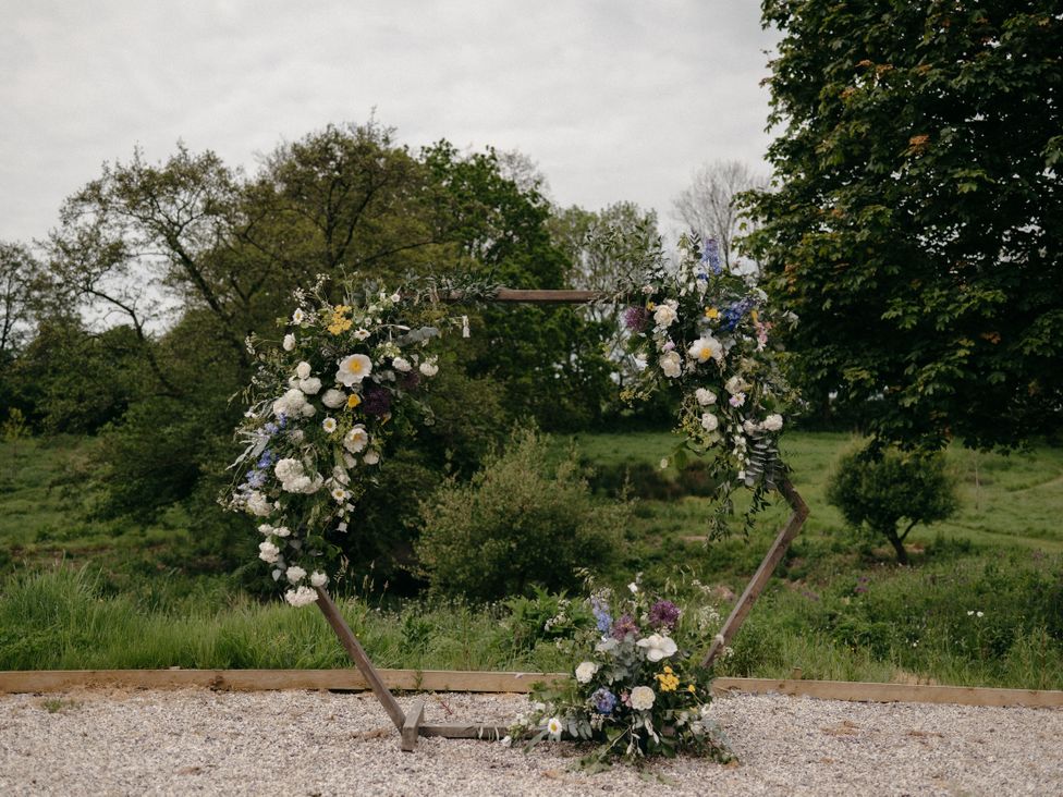 A decorative arch with flowers in a grassy area at Holwell Farmhouse in Bampton