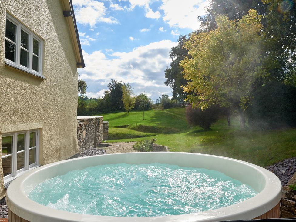 A hot tub with water outside a house at Holwell Farmhouse in Bampton
