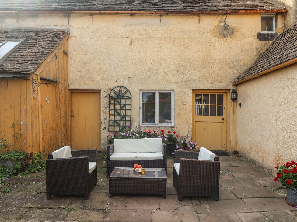 An outdoor seating area with a table and flowers at Badminton Farm Cottage