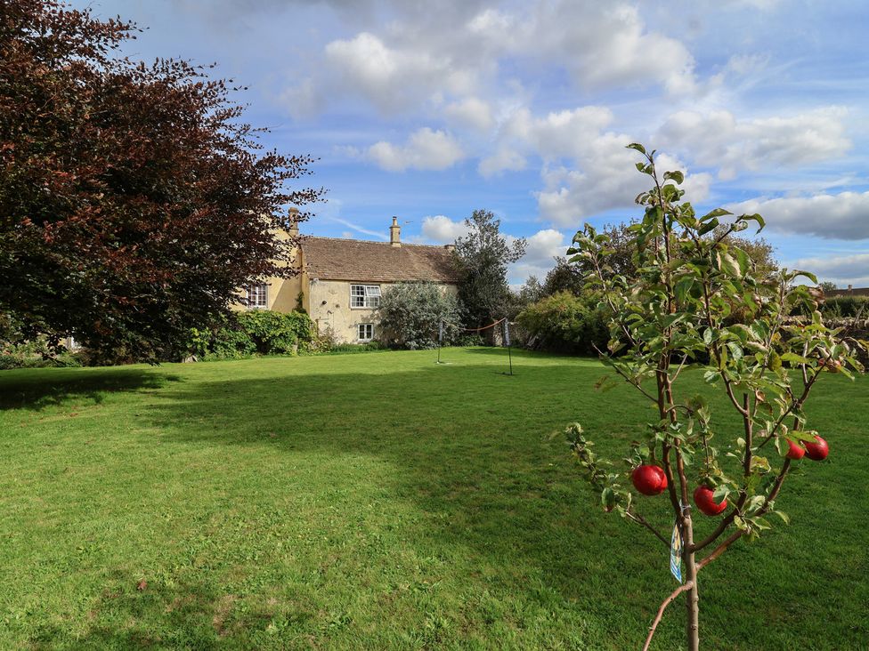 A garden with a house and trees at Badminton Farm Cottage