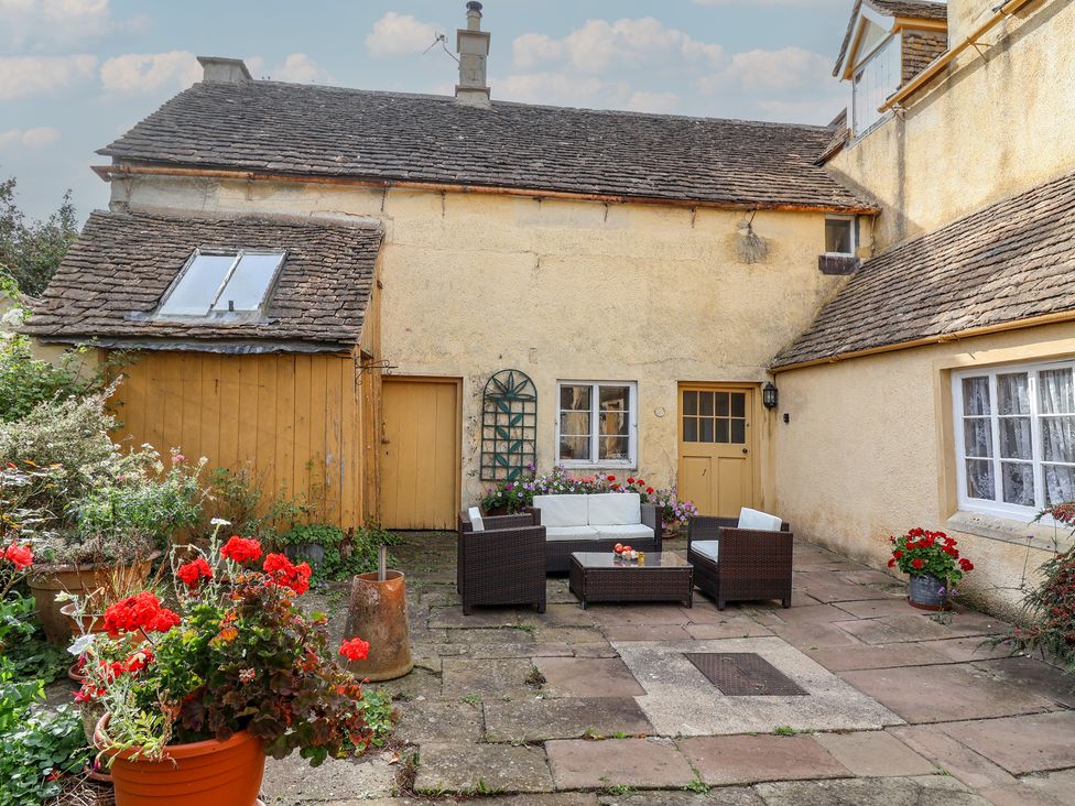 An outdoor seating area with a table and planters at Badminton Farm Cottage