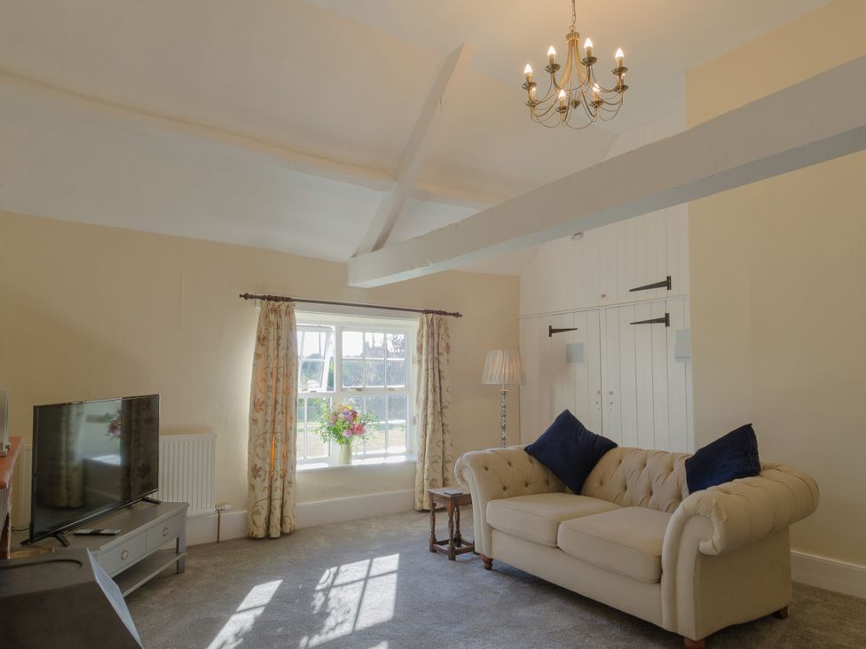 A living room with a sofa and television at Badminton Farm Cottage Acton Turville