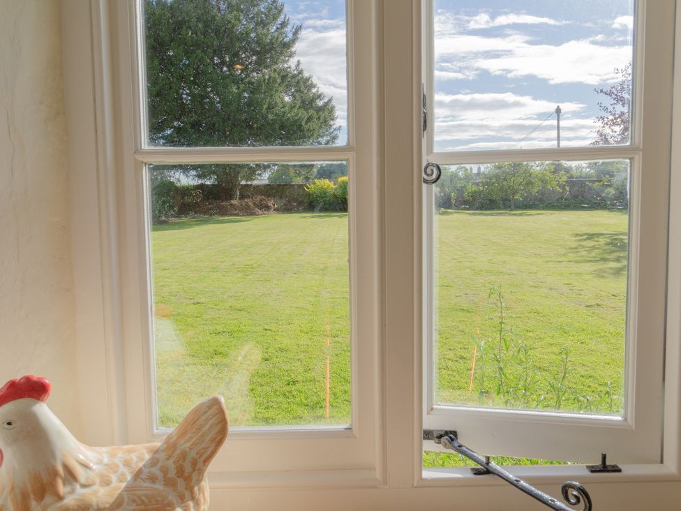 A view of a garden through a window at Badminton Farm Cottage in Acton Turville
