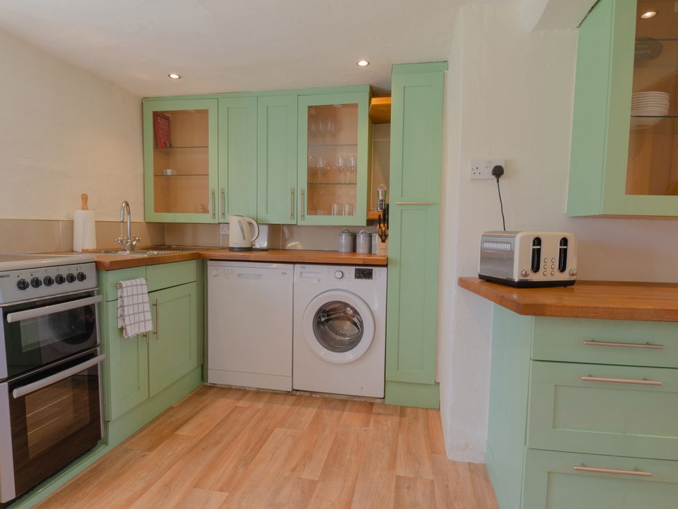 A kitchen with an oven, washing machine, and kettle at Badminton Farm Cottage in Acton Turville